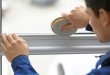 Young worker applying rubber strip onto window in office