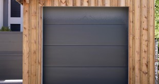 Modern car garage sectional door in dark grey of wooden building house