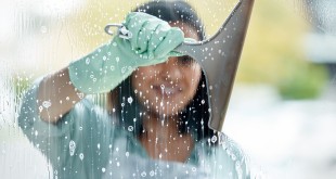 Make sure your squeegee is clean. Shot of a young woman cleaning her windows