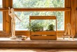 Sunny glass and wooden balcony with potted houseplant.